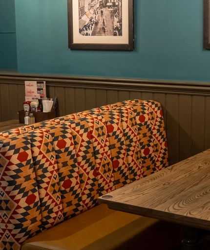 An interior restaurant seating area at The Tamar, with upholstered booth seats, and framed artwork on the wall.
