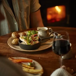 Crispy chicken, served with hassel back potatoes, on a table.