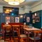 The interior restaurant seating area of the Royal George; with an upholstered booth seat, and a large TV on the wall above it.