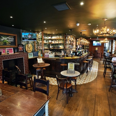 The interior bar and restaurant seating area with TV and fireplace at The Albanach.