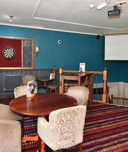 Interior dining area of a pub with a dartboard.