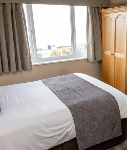 A interior double hotel bedroom with wardrobe, bedside tables and lamp at The Commodore.