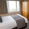 A interior double hotel bedroom with wardrobe, bedside tables and lamp at The Commodore.