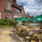 The exterior facade, signage, and beer garden seating area of the Golden Hind, with wooden picnic tables, shade umbrellas, and string lights.