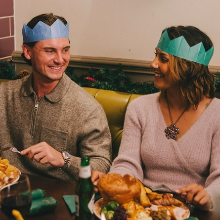 An image of a group of friends sat at a table enjoying festive main dishes and various drinks within the interior restaurant seating area at a Pub & Carvery venue.