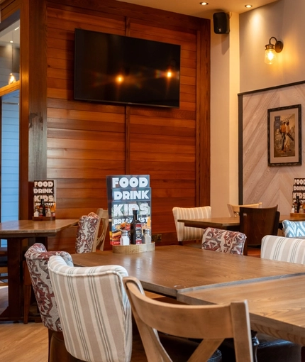 An interior restaurant seating area at The Wrekin Giant in Telford, with a TV on one wall, and framed artwork on another.
