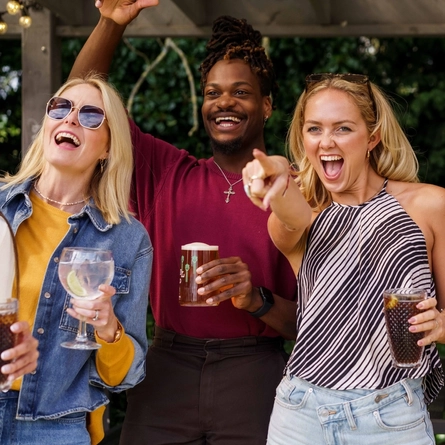 An exterior shot of a group of people with various drinks during the Q3 Live Music Event at one of the Greene King Pubs.