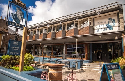 The exterior facade, signage and beer garden seating area of The Merlin in Edinburgh.