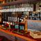 The wood panelled bar inside The London Apprentice in Isleworth, with bar stool seating, golden drinks trays on the counter, and glasses hanging in racks above it.