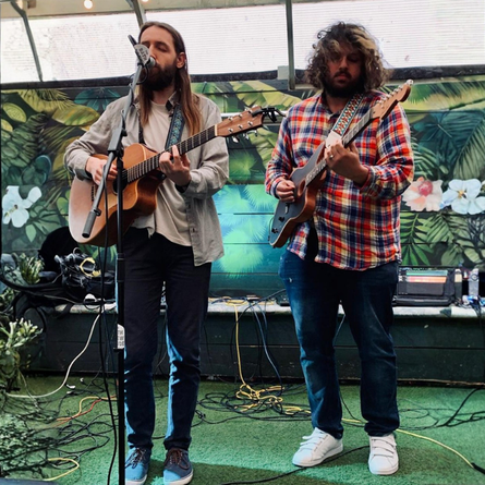 An image showing 2 people stood on a stage playing guitars to advertise a live music What's On event at The Cart & Horses.