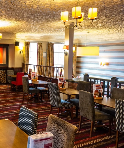 Interior dining area of a pub with a fireplace.