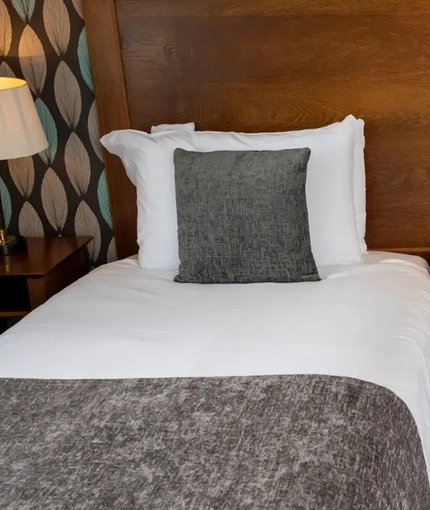 A interior twin hotel bedroom with two single beds, bedside tables and lamps at The Commodore.