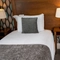 A interior twin hotel bedroom with two single beds, bedside tables and lamps at The Commodore.