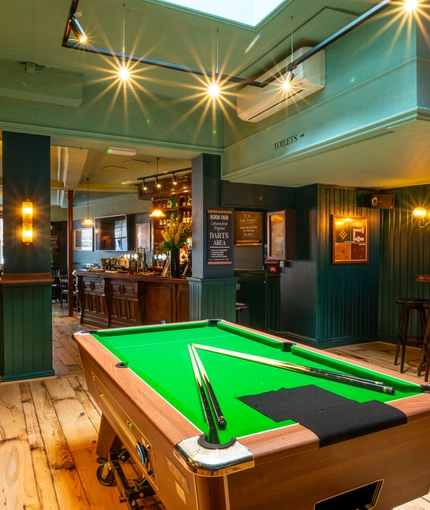 The interior games area at the Lord Raglan, with a pool table, and a view of the bar.