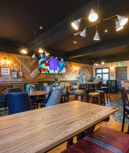 The bar and interior restaurant seating area at The Talbot Inn in Mansfield, with a dartboard, and a TV on the wall.