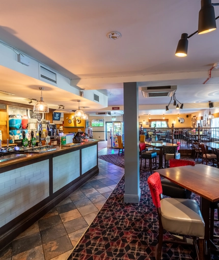 Interior dining area of a pub with a bar and a TV.