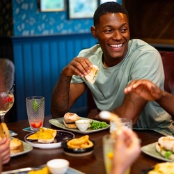 An image of various food and drinks being enjoyed within the interior restaurant seating area at a Community Pubs With Food venue.