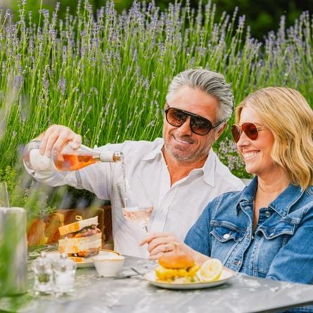 An image of two people enjoying two dishes from the lunch menu and rose wine within the exterior beer garden seating area at a Crafted venue.