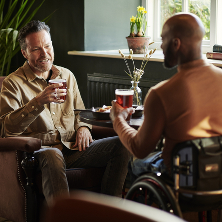 2 People sat a table talking, they have a pint. 