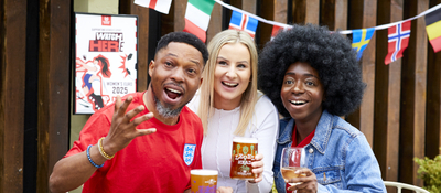 A mixed group of people, sitting at an outdoor table, reacting to a sport event.