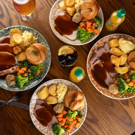 Plates of Sunday Roast on a wooden table of a pub