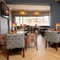 An interior restaurant seating area at The Heron; with wooden flooring, upholstered chairs, and a TV on the wall.