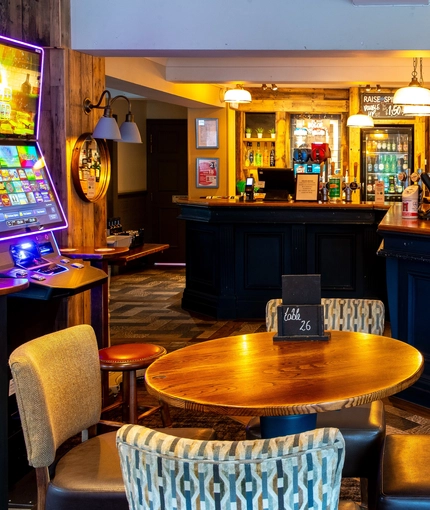Interior dining area of a pub with a bar and a gambling machine.