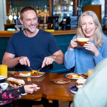 An image of a group of people sat at a table within the restaurant area with a breakfast dishes and drinks available at Urban Social venues.