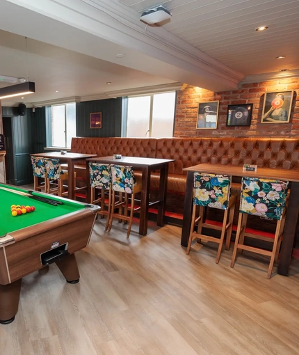 A pool table and slots machine next to some restaurant tables in The Brocklehurst Arms.