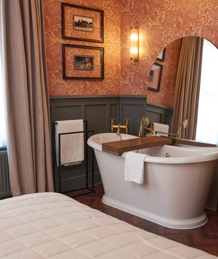 Hotel room with free standing roll top bath and large mirror