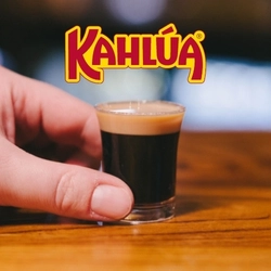A banner showing the Kahlua logo above a hand holding a shot glass of Guinness.