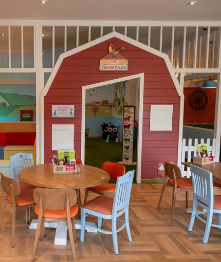 The interior restaurant seating area with tables, chairs and children's Farmyard themed play area at The Farmhouse Kitchen Willington.
