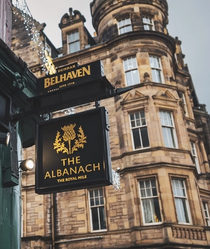 A close up view of the pub sign hanging on an exterior wall of the Albanach in Edinburgh.