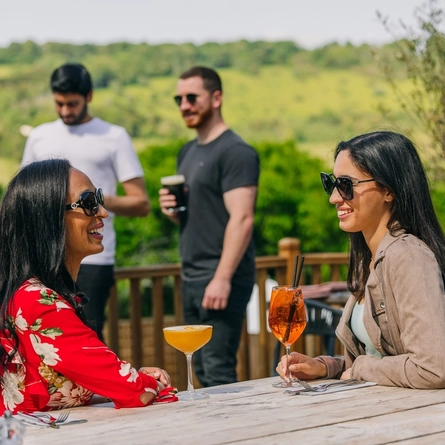 two women drinking a cocktail in the beer garden of a pub