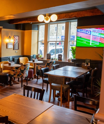An interior restaurant seating area at The Red Lion, with a TV on the wall, and a dog treat station.