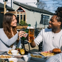 Friends enjoying a meal and drinks in the exterior seating area and beer garden from the new Spring/Summer menu at Flaming Grill.