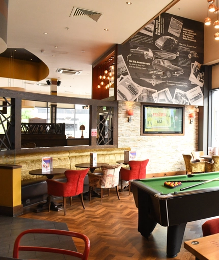 Interior dining area of a pub with a TV and a pool table.