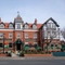 A view from across the road of the exterior facade, signage, and beer garden seating area of The Victoria in Lytham St Annes, with shade umbrellas on some of the tables.