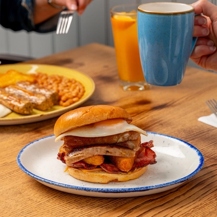 A plated breakfast bap  and Full English Breakfast, on an indoor table.