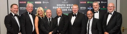 A group of people in suits and dresses standing behind a rope at an awards night.