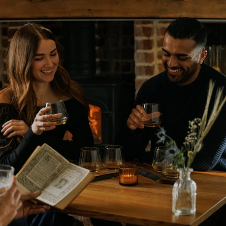 An image of 3 customers enjoying a Burns Night Whiskey flight board sat at a table within the interior restaurant seating area of The Crown.