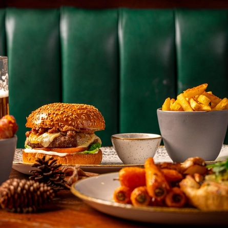 A plated burger on a festive decorated table with a pint of beer.