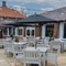 A paved exterior seating area at The Vine Inn, with wooden tables and chairs, shade umbrellas, and string lights overhead.