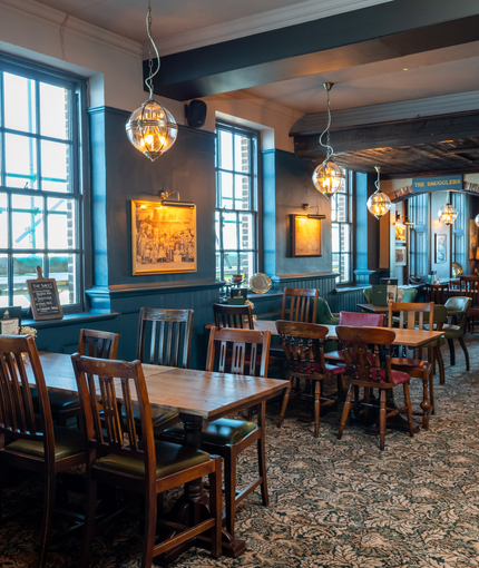 An image of the interior restaurant seating area with tables, chairs, brick cast iron fireplace and view from the window over the sea at The Spice Island.