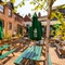 The exterior paved beer garden seating area at The Windmill Inn in York, with wooden picnic tables, shade umbrellas, and string lights overhead.