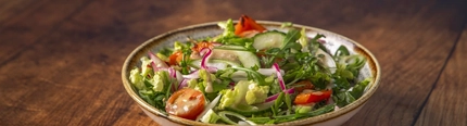 House salad served in a bowl, sitting on a wooden table.