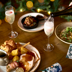An image of drinks being poured with 3 festive dishes sat on a table within the interior restaurant seating area at a Chef & Brewer venue.