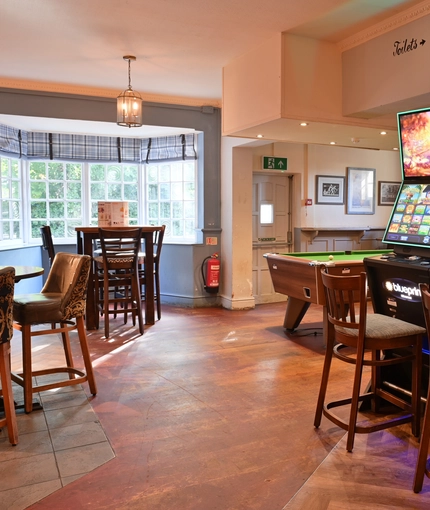 Interior dining area of a pub with two gambling machines and a pool table.