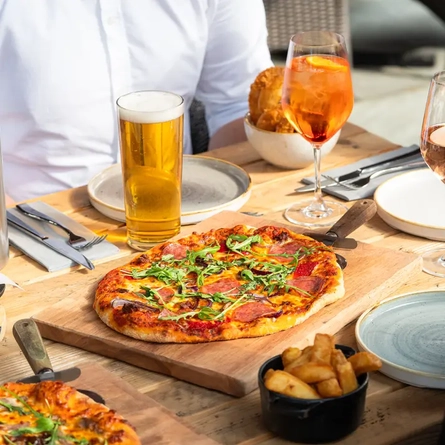 Table with a variety of pizzas and drinks