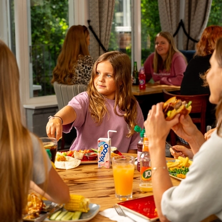 A family sat at an indoor table enjoying a meal and drinks at a Hungry Horse venue.